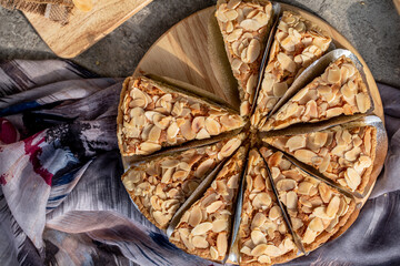 Cutting for serving of homemade almond tart on wooden board, top view. - obrazy, fototapety, plakaty