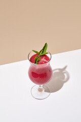 Raspberry Smoothie with mint on white table. Summer healthy drink concept. Beige wall and white table with sunshine and harsh shadow. Berry Smoothie menu