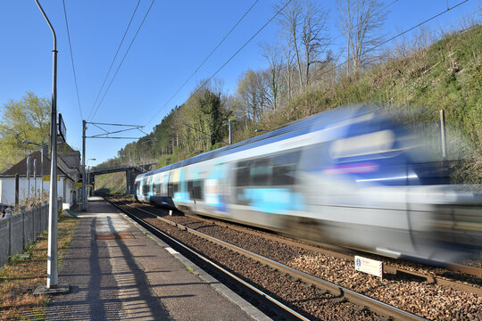 Passage &agrave; grande vitesse d'un Ter dans une gare sur la ligne Paris-Rouen-Le Havre. Effet de fil&eacute;