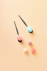 Spoons with makeup sponges on color background
