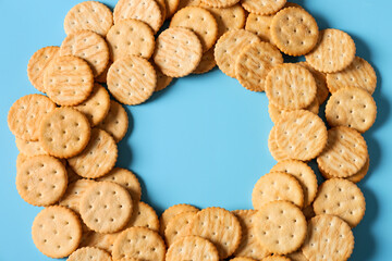 Frame made of tasty crackers on color background