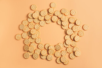 Frame made of tasty crackers on color background