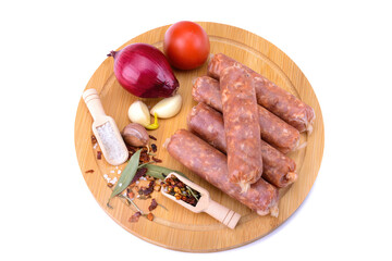 Raw homemade pork sausages laid out with spices on a round wooden board, isolated on a white background.Selective focus.top view.