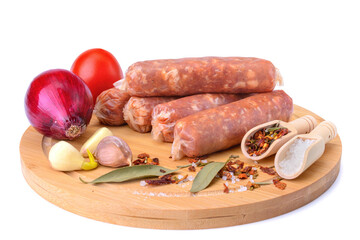 Raw homemade pork sausages laid out with spices on a round wooden board, isolated on a white background.Selective focus.top view.