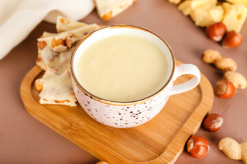 Cup with hot white chocolate on color background