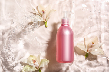 Bottle of cosmetic product and flowers in water on light background