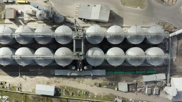 Grain elevator and silos near the river aerial view. Aerial view large waterfront grain storage facility with concrete silos and train yard. 