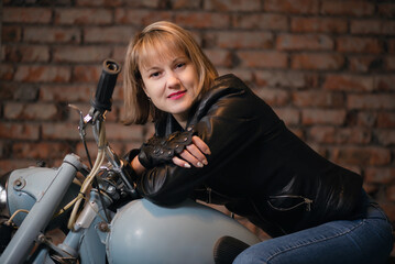 Obraz na płótnie Canvas Happy woman a motorbiker is sitting on the motorcycle and smiling.