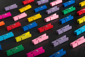 Bright multi-colored clothespins on black background. Diversity