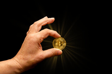 Menschliche Hand hält Bitcoin-Münze mit Sonnenstern