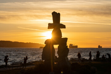 Inukshuk stone sculpture in the sunset time at English Bay Beach, Vancouver City beautiful landscape. British Columbia, Canada. - obrazy, fototapety, plakaty