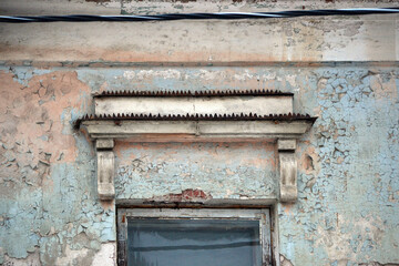 Elements of the architectural decor of the building. A fragment of the wall of an old stone house with peeling plaster.