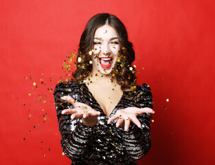 Holiday and party concept: beautiful young woman wearing evening dress standing under confetti rain...