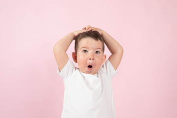 Close up portrait of surprised little boy on pink background. Different children's emotions concept