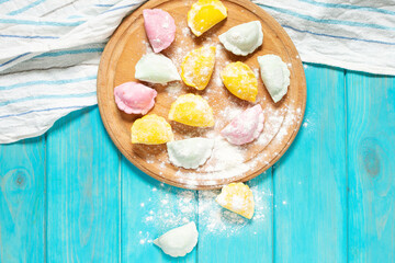 Multi colored dumplings from color dough stuffed with meat on blue wooden background