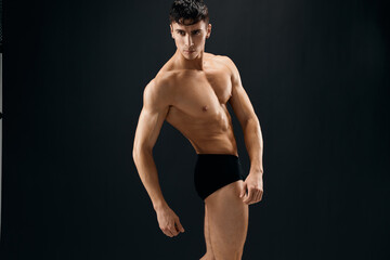 attractive male bodybuilder with muscular body posing dark background