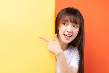 Young asian girl overlapping yellow background on orange background