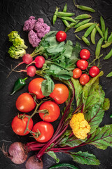 Summer salad ingredients. Raw vegetables, shot from above on a dark background