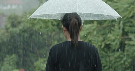 Woman is holding umbrella walking alone under the rain