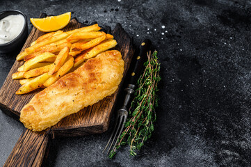 Fish and chips dish with french fries on wooden board. Black background. Top view. Copy space