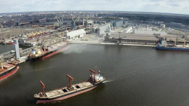 Aerial View Of Cargo Ship Docking.  Ship Loading. Aerial view of cargo ship in dock port factory. Corn in bulk carrier hold. Casting hold of corn. Elevator crane loads ship bulk carrier with corn. 