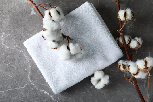 Cotton plant branches and towel on gray textured background