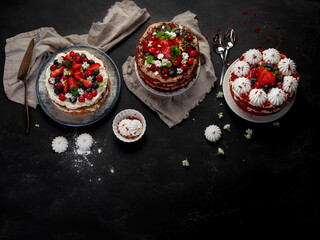 Assorted delicious and colorful homemade cakes with different type of filling on black background.