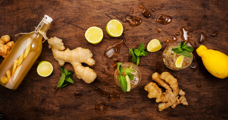 Ginger Ale Cocktail with Beer, Lime, Lemon and Mint in glaass on wooden table, top view banner