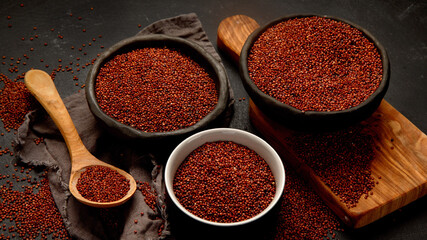 Red quinoa seeds on dark background. Healthy vegan food concept.