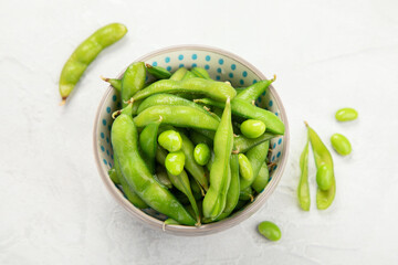 Raw edamame soya beans with salt and sauce on light gray background.