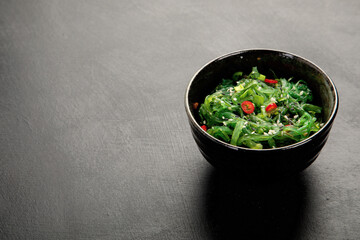 Wakame seaweed with sesame and chilli on gray background. Asian food concept.