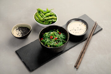 Wakame seaweed with sesame and chilli on gray background. Asian food concept.