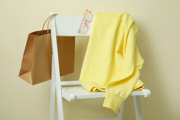 Wooden chair with yellow sweatshirt, bag and glasses