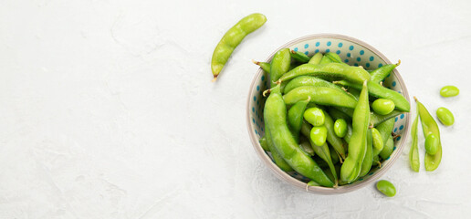 Raw edamame soya beans with salt and sauce on light gray background.