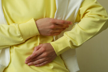 Young woman in yellow sweatshirt against beige background, close up