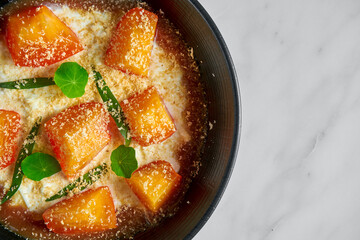 An appetizing and unusual Italian dessert - Stracciatella di bufala with persimmon and jam, served in a black plate on a marble background.