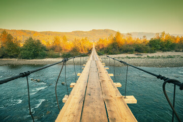 Wooden hanging rope bridge over mountain river