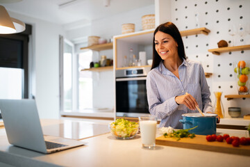 Happy beautiful woman learning to cook with online course at home