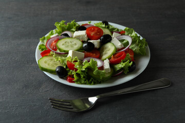 Plate of greek salad and fork on dark wooden background