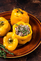 Yellow sweet bell pepper stuffed with meat, rice and vegetables. Dark background. Top view