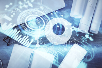 Business theme hologram drawings over computer on the desktop background. Top view. Multi exposure....