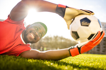 happy multicultural hispanic soccer player smiling and wear red sporty suit outdoor sunny day