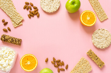 Frame of various healthy snacks on pink background, space for text