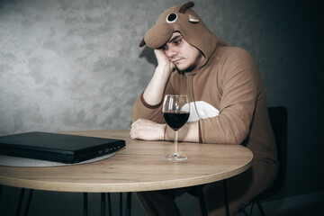 Office worker in cosplay costume of a cow. Guy in the funny animal pyjamas near the a glass of...