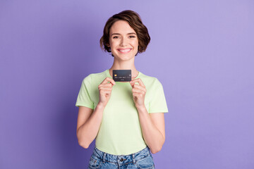 Portrait of attractive cheerful brown-haired girl holding in hands bank card ad isolated over...