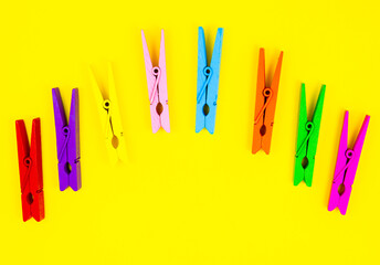 Colorful wooden clothespins on yellow background. Close up, copy space. Minimalism, original and creative photo. Be another. Individuality concept. Vertical Wallpaper for smartphone.