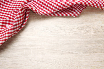 Obraz premium Red checered cloth on wooden table top view. Picnic towel on light wood texture background empty advertisement space.