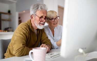 Senior woman helping senior man to use computer