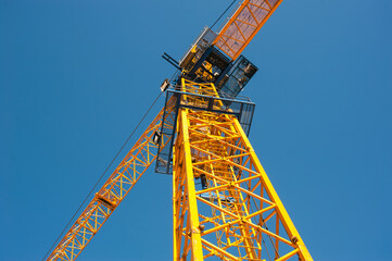 Fototapeta na wymiar iron cabin of a yellow crane against a blue sky