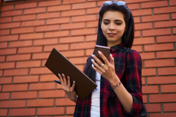 Young Caucasian woman with sketchbook browsing social media via modern cellphone gadget using 4g internet in city, millennial female student spending leisure time for online blogging via mobile phone